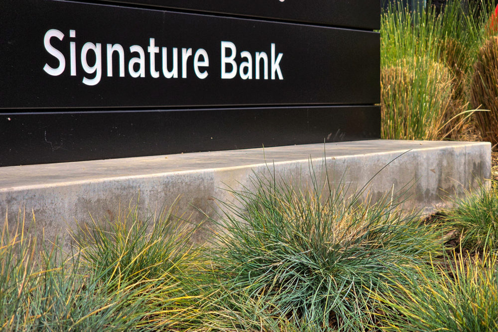 A sign is displayed outside an office building housing a branch of Signature Bank. (Damian Dovarganes/AP)